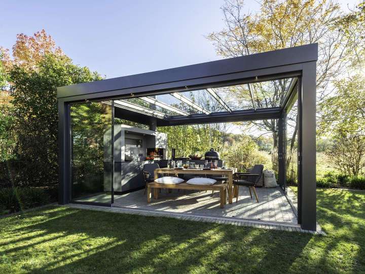 Freistehendes Glashaus mit Outdoorküche in einem Garten